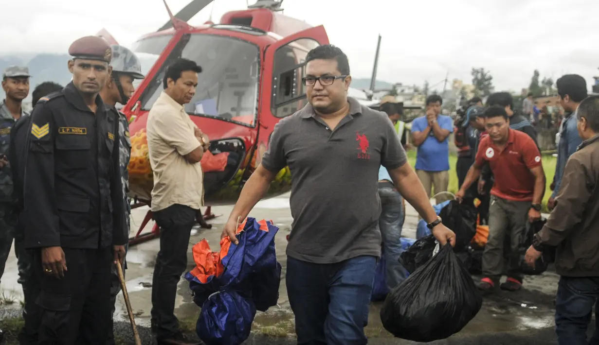 Petugas membawa barang milik korban tewas jatuhnya helikopter, di sebelah utara Ibu Kota Nepal, Kathmandu, Senin (8/8). Helikopter yang mengangkut enam warga lokal menuju Kathmandu itu hilang kontak 30 menit setelah lepas landas. (AFP PHOTO/BIKASH Karki)