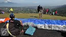 Pemandu wisata menyiapkan parasut untuk diterbangkan di Puncak Pass, Bogor, Jumat (6/4). Sebagian warga memanfaatkan libur panjang akhir pekan ini dengan bermain Paralayang. (Liputan6.com/Johan Tallo)