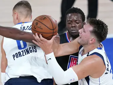 Pebasket Dallas Mavericks, Luka Doncic, berebut bola dengan pemain Los Angeles Clippers, Reggie Jackson, pada gim kedua playoff NBA 2020 di AdventHealth Arena, Kamis (20/8/2020). Maverick menang 127-114 atas LA Clipppers. (AFP/Ashley Landis-Pool/Getty Images)