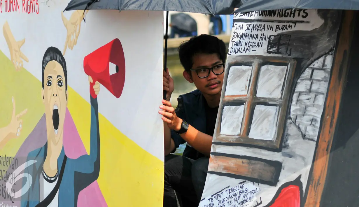 Mahasiswa Trisakti saat menggelar aksi dengan memajang gambar mural bertema kemanusiaan di Bundaran Patung Kuda, Jakarta, Kamis (12/5). Aksi ini bertujuan untuk memperingati tragedi trisakti 12 Mei 98. (Liputan6.com/Yoppy Renato)