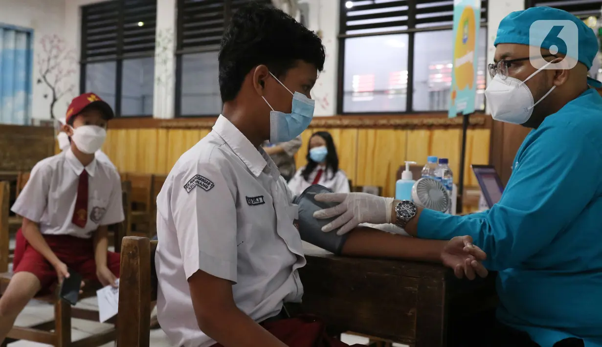 Petugas menyuntikan vaksin COVID-19 Pfizer kepada seorang siswa di SDN Panunggangan 5, Pinang, Kota Tangerang, Selasa (19/10/2021).  Pelaksanaan vaksinasi untuk pelajar usia 12 tahun ini dilakukan dalam rangka persiapan pelaksanaan pembelajaran tatap muka (PTM). (Liputan6.com/Angga Yuniar)