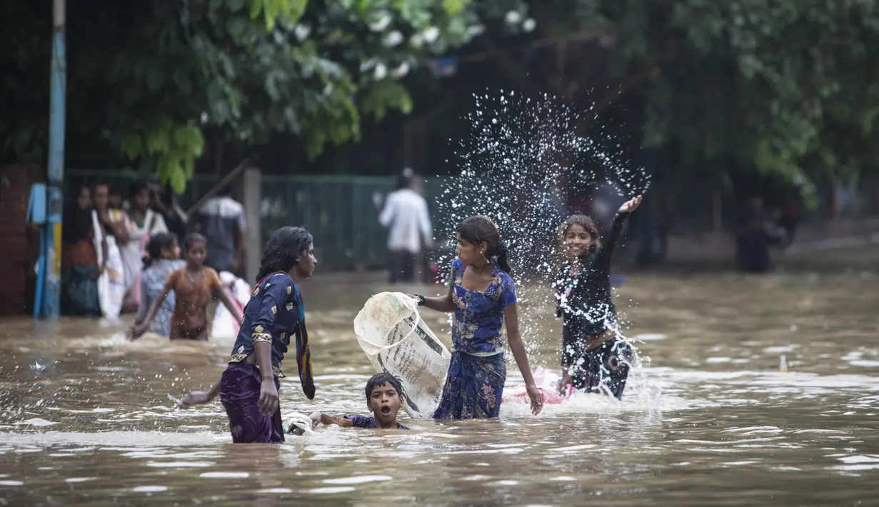 Anak-anak bermain di jalan yang tergenang air setelah hujan monsun di Gurgaon di pinggiran New Delhi (19/8/2020). Jumlah korban dari banjir tahunan di seluruh Asia Selatan naik menjadi hampir 1.300. (AFP/Xavier Galiana)