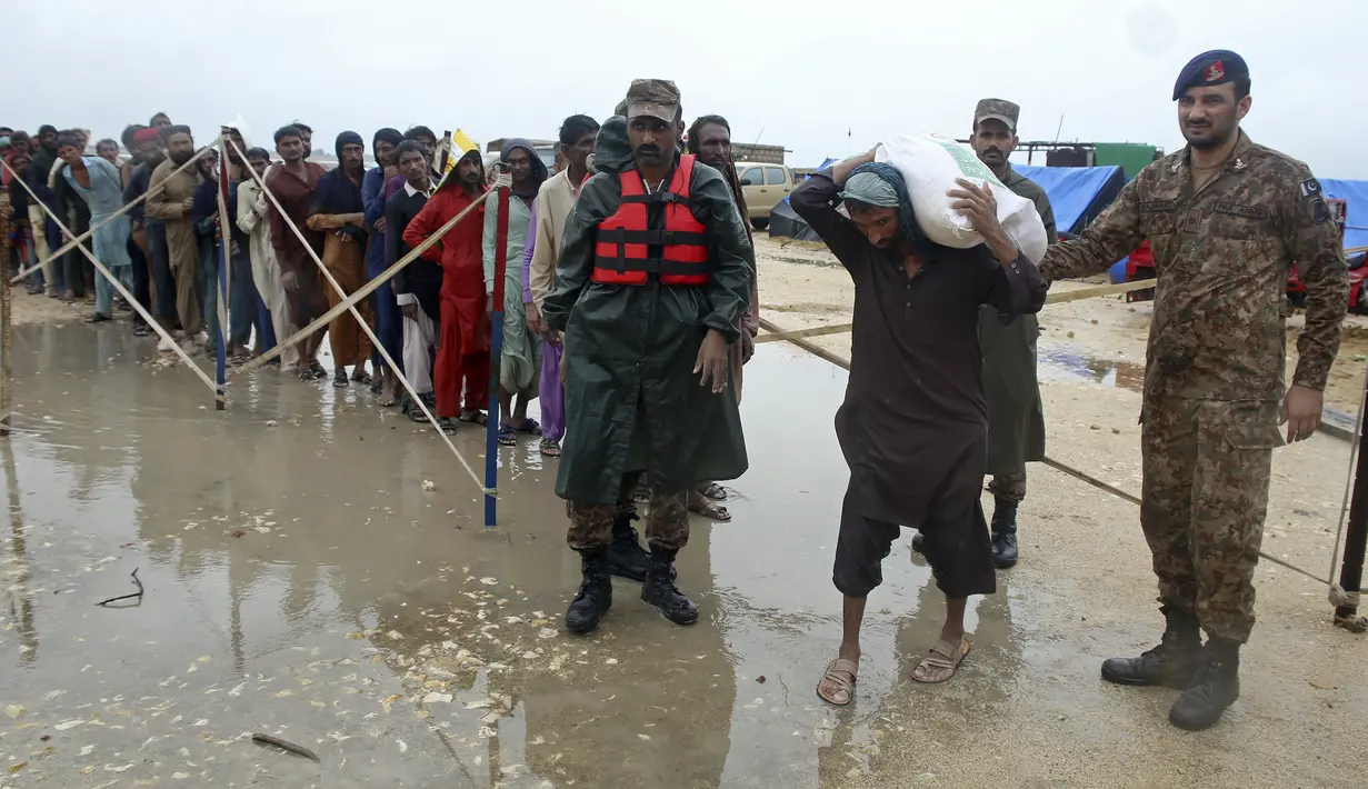 Tentara membagikan makanan dan barang-barang lainnya kepada orang-orang terlantar di sebuah kamp bantuan di daerah yang dilanda banjir di distrik Jamshoro, di Pakistan selatan, Rabu (24/8/2022). Hujan deras telah memicu banjir bandang dan mendatangkan malapetaka di banyak tempat. (AP Photo/Pervez Masih)