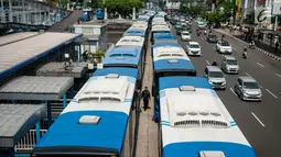 Seorang warga melewati Bus Transjakarta mogok kerja mengantarkan penumpang di Halte Harmoni, Jakarta (12/6). Akibat aksi mogok kerja tersebut, operasional bus Transjakarta menjadi terganggu. (Liputan6.com/Gempur M Surya)