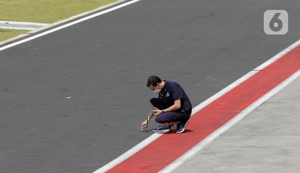 Salah satu official tim mengukur suhu aspal sekitar pit lane saat sesi Warm Up MotoGP di Pertamina Mandalika International Street Sirkuit, Nusa Tenggara Barat, Minggu (20/3/2022). (Liputan6.com/Helmi Fithriansyah)