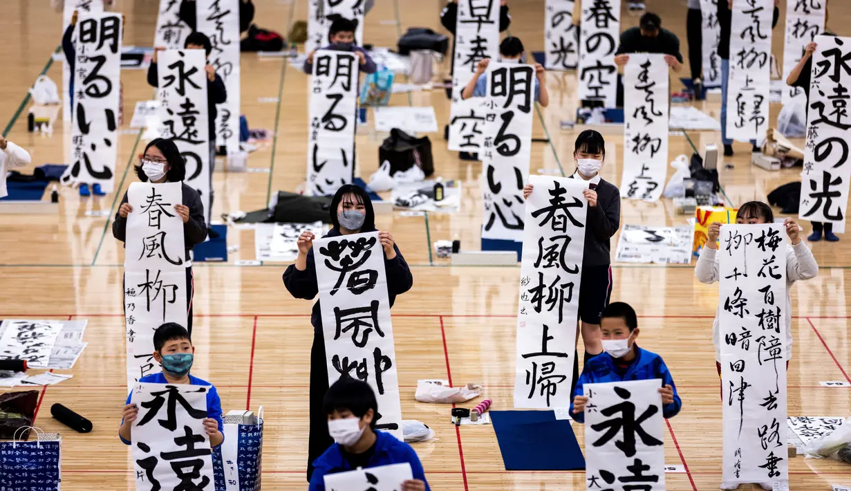 Peserta menampilkan tulisan Jepang mereka selama kontes kaligrafi Tahun Baru tahunan di Tokyo (5/1/2022). Lebih dari 3.000 kaligrafer, yang telah memenuhi syarat dalam kompetisi tingkat nasional di seluruh Jepang, ikut serta dalam kontes tahunan untuk merayakan tahun baru. (AFP/Behrouz Mehri)