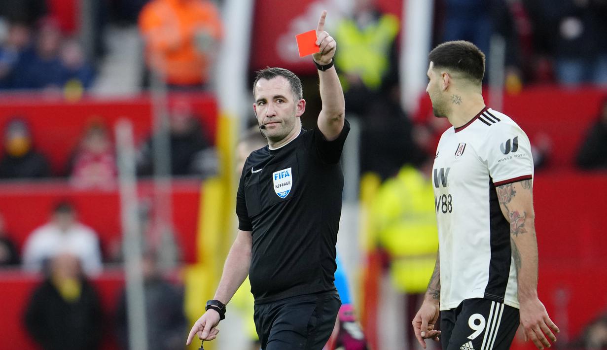 Pemain Fulham, Aleksandar Mitrovic (kanan), menatap wasit Chris Kavanagh yang memberikan kartu merah kepada Willian yang menghalau bola menggunakan tangannya untuk mencegah gawang timnya kebobolan dalam babak perempat final Piala FA 2022/2023 melawan Manchester United yang berlangsung di Old Trafford, Minggu (19/3/2023) malam WIB. (AP Photo/Jon Super)