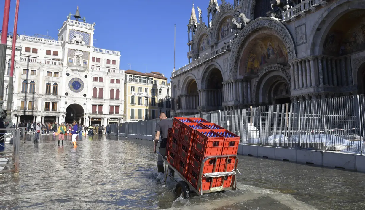 Orang-orang berjalan di St. Mark's Square yang terendam banjir di Venesia, Italia, Jumat (5/11/2021). Setelah Venesia mengalami banjir terparah kedua dalam sejarahnya pada November 2019, kota itu dibanjiri empat kali pasang luar biasa dalam waktu enam minggu. (AP Photo/Luigi Costantini)