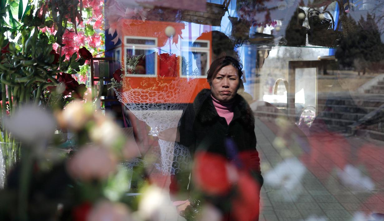 Seorang wanita terlihat di kaca jendela sebuah kios yang menjual bunga dalam perayaan Hari Perempuan Internasional di Pyongyang, Korea Utara, Jumat (8/3). (AP Photo/Dita Alangkara)