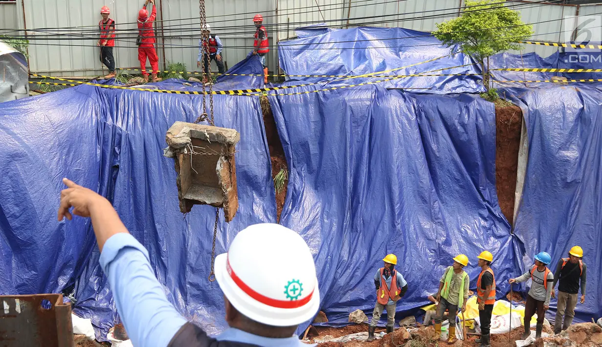 Pekerja konstruksi mengangkat beton pembangunan tiang pancang proyek LRT dan flyover Pancoran yang longsor di Jakarta, Jumat (13/10). Tidak ada korban jiwa dalam peristiwa longsor yang terjadi Kamis (12/10/2017) tersebut. (Liputan6.com/Immanuel Antonius)