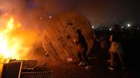 Demonstran menggulung gulungan kabel kayu ke barikade yang terbakar saat protes RUU Pensiun di Paris, Prancis, Jumat (17/3/2023). (AP Photo/Lewis Joly)