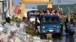 Dua mobil bak terbuka mengangkut para pekerja pulang ke rumah dari tempat kerja di sebuah pabrik di dekat desa Trapang Anchanh, di luar Phnom Penh, Kamboja (27/10). (AP Photo/Heng Sinith)