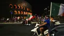 Suporter Italia menaiki motor di depan Colosseum kuno Roma merayakan kemenangan atas Spanyol pada pertandingan semifinal Euro 2020 Stadion Wembley, London, Inggris, Rabu (7/7/2021). Gli Azzurri berhak ke final Piala Eropa 2020. (AP Photo/Alessandra Tarantino)