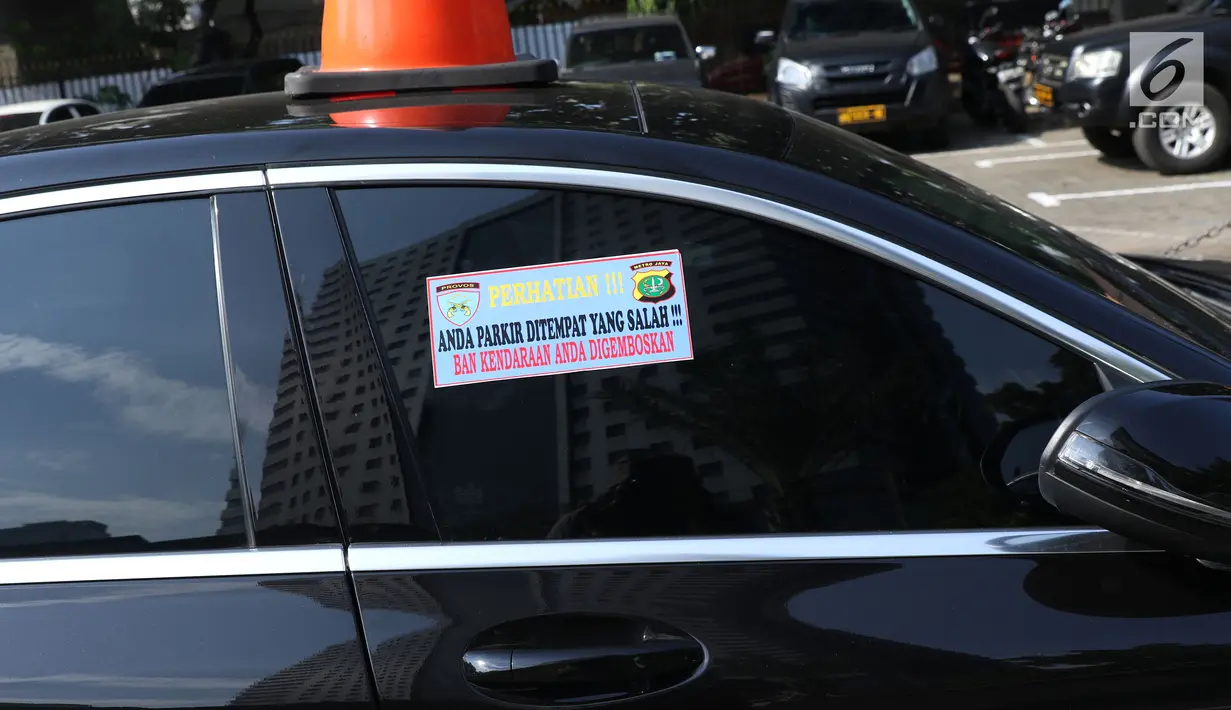 Stiker sanksi tertempel di mobil yang parkir di halaman Polda Metro Jaya, Senin (19/11). Polda Metro Jaya menerapkan sanksi penggembosan dan penempelan stiker bagi kendaraan yang parkir sembarangan di halaman Polda Metro. (Liputan6.com/Helmi Fithriansyah)