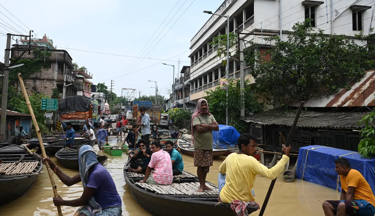 Warga menaiki perahu di atas jalan yang terendam banjir menyusul hujan lebat di Ghatal, distrik Paschim Medinipur, sekitar 100 km dari Kolkata (2/8/2021). Banjir parah akibat hujan lebat membuat jalanan di Ghatal berubah bak sungai. (AFP/Dibyangshu Sarkar)