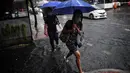 Orang-orang berjalan di jalan yang banjir saat hujan deras di Bangkok (23/9/2020). (AFP/Mladen Antonov)