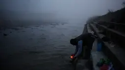 Seorang pria menghayutkan lilin di sungai Bagmati saat ritual Gaya Aunsi di Kathmandu, Nepal (21/12). Mereka percaya, dengan menggelar ritual ini dapat membantu keluarga mereka yang telah meninggal untuk menuju surga (AP Photo/Niranjan Shrestha)