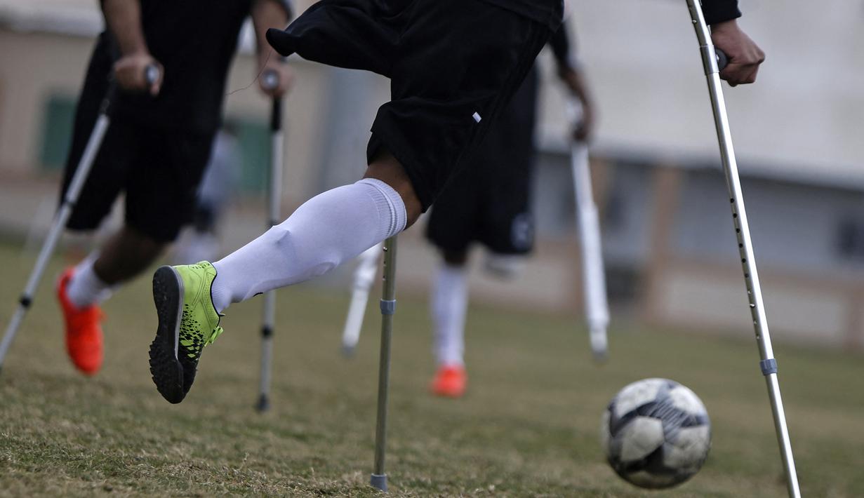 Seorang pemain klub Al-Jazeera (hitam) menggiring bola dalam pertandingan final kejuaraan lokal sepak bola korban amputasi melawan Al-Abtal yang diselenggarakan oleh Komite Palang Merah Internasional (ICRC), di tengah pandemi COVID-19, di Kota Gaza, Palestina, (18/3/2021). (AFP/Mohammed Abed)