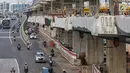 Pengendara bermotor melintasi lokasi pembangunan jalur kereta ringan atau Light Rail Transit (LRT) Jabodebek rute Cawang-Dukuh Atas di Cawang, Jakarta, Senin (29/4/2019). Pembangunan jalur LRT Cawang-Kuningan-Dukuh Atas yang mencapai 47,95 persen (data akhir Maret 2019). (Liputan6.com/Johan Tallo)