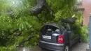 Sebuah mobil rusak tertimpa pohon yang tumbang setelah hujan lebat di New Delhi, India (1/9/2021). Stasiun cuaca mencatat curah hujan 112,1 mm dalam 24 jam yang berakhir pada hari Rabu pukul 08.30 waktu setempat. (AFP/Prakash Singh)