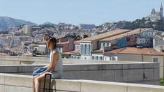 Seorang wanita duduk dengan latar belakang suasana kota di Marseille, Prancis, Minggu (3/7/2016). Marseille merupakan daerah pesisir di selatan Prancis dengan pesona keindahan alam. (Bola.com/Vitalis Yogi Trisna)