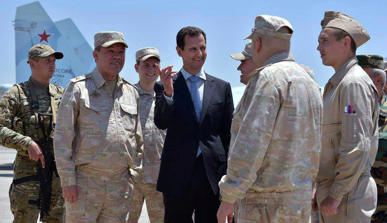 Presiden Suriah Bashar al-Assad berbincang dengan pasukan Rusia saat mengunjungi pangkalan udara Rusia di Khmeimim, Selasa (27/6). Kunjungan ini merupakan yang pertama kalinya Assad lakukan ke pangkalan. (Syrian Presidency via Facebook)