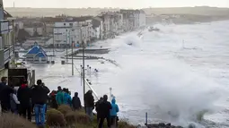 Sejumlah warga berkumpul menyaksikan debur ombak yang disebabkan badai Eleanor di pinggir laut Wimereux, utara Prancis (3/1). Badai Eleanor memaksa penghentian layanan transportasi dan kereta api.  (AFP Photo/Francois Lopresti)
