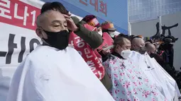 Pemilik usaha kecil dicukur rambutnya saat unjuk rasa menentang aturan jarak sosial pemerintah di dekat Kompleks Pemerintah di Seoul, Korea Selatan, Selasa (15/2/2022). Korea Selatan melaporkan jumlah kematian COVID-19 tertinggi dalam sebulan Selasa (15/2). (AP Photo/Ahn Young-joon)