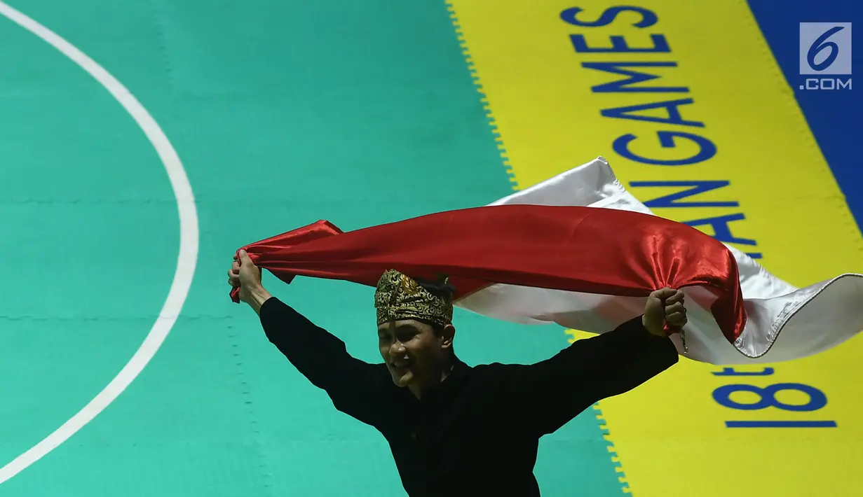 Pesilat Indonesia Sugianto membawa bendera merah putih usai meraih medali emas dalam babak final tunggal putra pencak silat seni Asian Games 2018 di Padepokan Pencak Silat Taman Mini Indonesia Indah (TMII), Jakarta, Rabu (29/8). (Merdeka.com/ Imam Buhori)