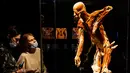 Pengunjung melihat salah satu karya seni yang dipajang dalam pameran anatomi tubuh manusia bertajuk 'Body Worlds' di Moskow, Rusia (24/3/2021). Pameran ini menjadi polemik dan menuai banyak kecaman lantaran menggunakan mayat manusia. (AFP/Dimitar Dilkoff)
