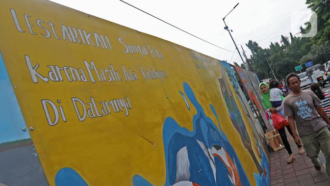 Pejalan kaki melintasi mural yang berisi pesan ajakan untuk menjaga lingkungan di Jalan Tambak, Manggarai, Jakarta, Selasa (11/2/2020). Mural tersebut bertujuan mengingatkan bahwa permasalahan lingkungan merupakan masalah serius yang harus dihadapi bersama. (Liputan6.com/Herman Zakharia)