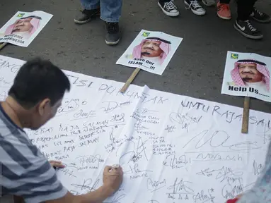 Pengunjung Car Free Day (CFD) menandatangani spanduk berisi petisi mendukung kedatangan Raja Salman, di Bundaran HI, Jakarta, Minggu (26/2). Petisi berisi harapan atas  kunjungan Raja Arab Saudi, Salman bin Abdulazis Al Saud. (Liputan6.com/Faizal Fanani)