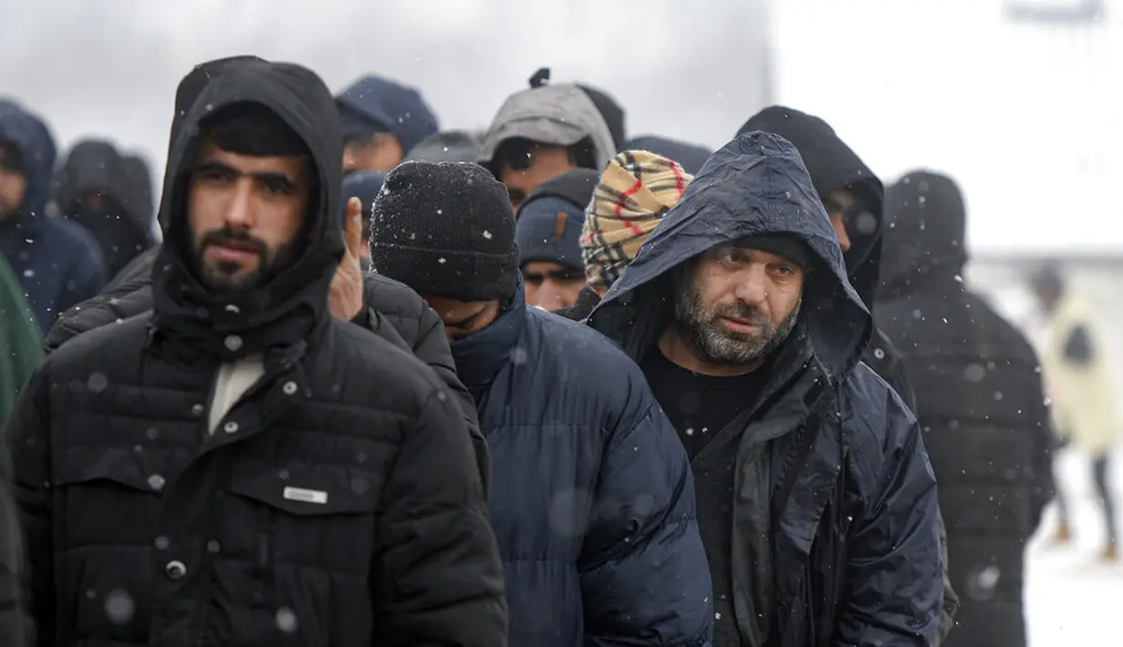 Para imigran mengantre untuk mendapatkan makanan selama hujan salju di Kamp Lipa, luar Bihac, Bosnia, Jumat (8/1/2021). Cuaca bersalju dan musim dingin telah membawa lebih banyak penderitaan bagi ratusan imigran yang terjebak selama berhari-hari di kamp tersebut. (AP Photo/Kemal Softic)