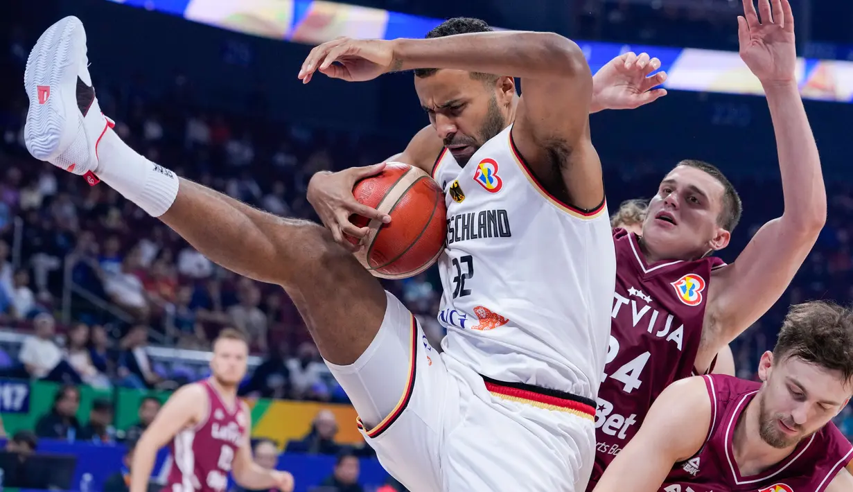 Pemain timnas basket Jerman, Johannes Thiemann (32) terjatuh ke arah pebasket Latvia Andrejs Grazulis saat mengambil bola selama perempat final Piala Dunia Bola Basket di Manila, Filipina, Rabu, 6 September 2023. (AP Photo/Michael Conroy)