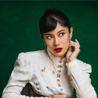 ian Sastrowardoyo dengan balutan kebaya Janggan bernuansa putih dengan detail kancing yang unik dan beberapa aksesori emas yang mewah dan menyempurnakan penampilannya. Di sini, Dian tampil bold dengan riasan flawless dan pulasan lipstik merah merona. [Foto: Instagram/therealdisastr]