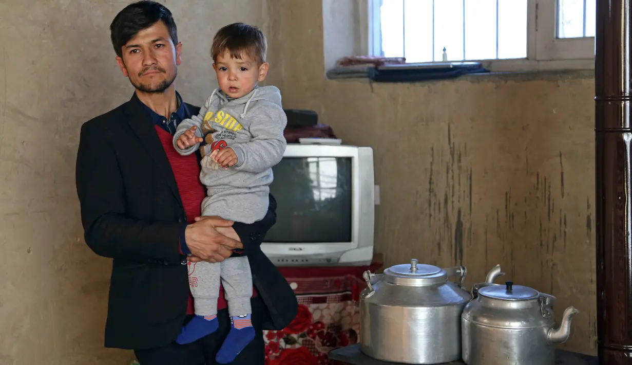 Asadullah Poya dan anak laki-lakinya, Donald Trump berpose di rumah kontrakannya di Kabul, Afghanistan, Kamis (15/3). Assadullah menamai anaknya Donald Trump karena melihat kemiripan pada anaknya yang berambut pirang dengan sang presiden. (AP/Rahmat Gul)