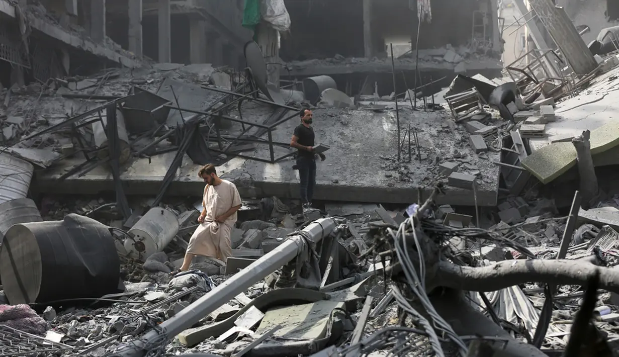 <p>Warga memeriksa kerusakan bangunan yang hancur akibat serangan udara Israel di Kota Gaza, Palestina, Senin (23/10/2023). (AP Photo/Abed Khaled)</p>