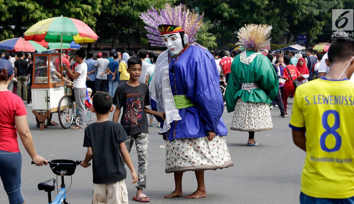 Pengamen ondel-ondel meminta sumbangan kepada warga di lokasi car free day, Jakarta, Minggu (21/5). Ramainya pengunjung CFD menyebabkan banyak pengamen mencari rezeki di kegiatan yang berlangsung setiap minggu tersebut. (Liputan6.com/Immanuel Antonius)