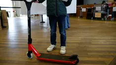 Seseorang memegang surat suara dan skuter elektrik selama sesi pemungutan suara "citizen vote" untuk skuter listrik yang berseliweran di jalan, di balai kota distrik ke-17 di Paris, Minggu (2/4/2023). (Photo by Geoffroy Van der Hasselt / AFP)