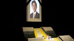 Potret mantan Perdana Menteri Jepang Shinzo Abe terlihat pada altar saat pemakaman kenegaraannya di Nippon Budokan, Tokyo, Jepang, 22 September 2022. Sekitar 60 persen orang mengatakan mereka tidak mendukung prosesi pemakaman tersebut. (AP Photo/Eugene Hoshiko, Pool)