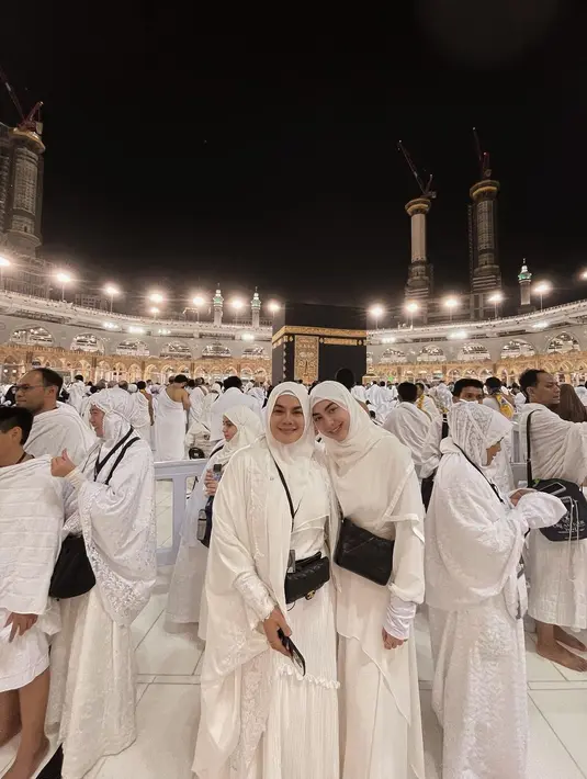 Sarita Abdul Mukti bersama Shania Salsabila, berpose mengenakan pakaian serba putih dengan latar belakang Kakbah. Sepertinya mereka baru saja menyelesaikan tawaf. (Foto: Instagram/@_shaniasalsabila)