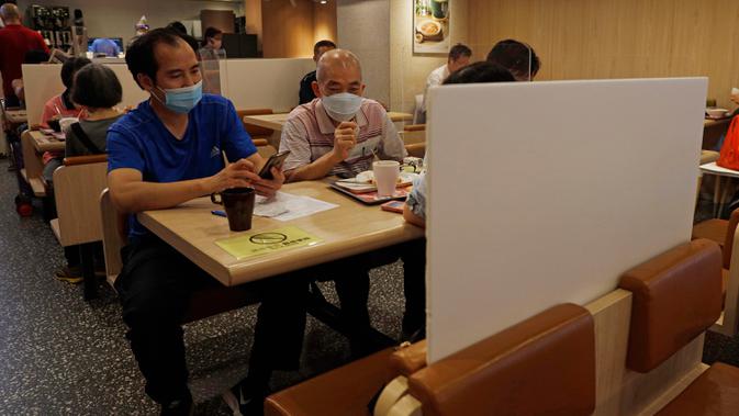 Orang-orang yang memakai masker menikmati makanan di restoran berpartisi di Hong Kong, Rabu (22/7/2020). Hong Kong telah mewajibkan penggunaan masker di semua area publik tertutup termasuk mal dan pasar seiring penambahan kasus baru harian Covid-19. (AP Photo/Kin Cheung)