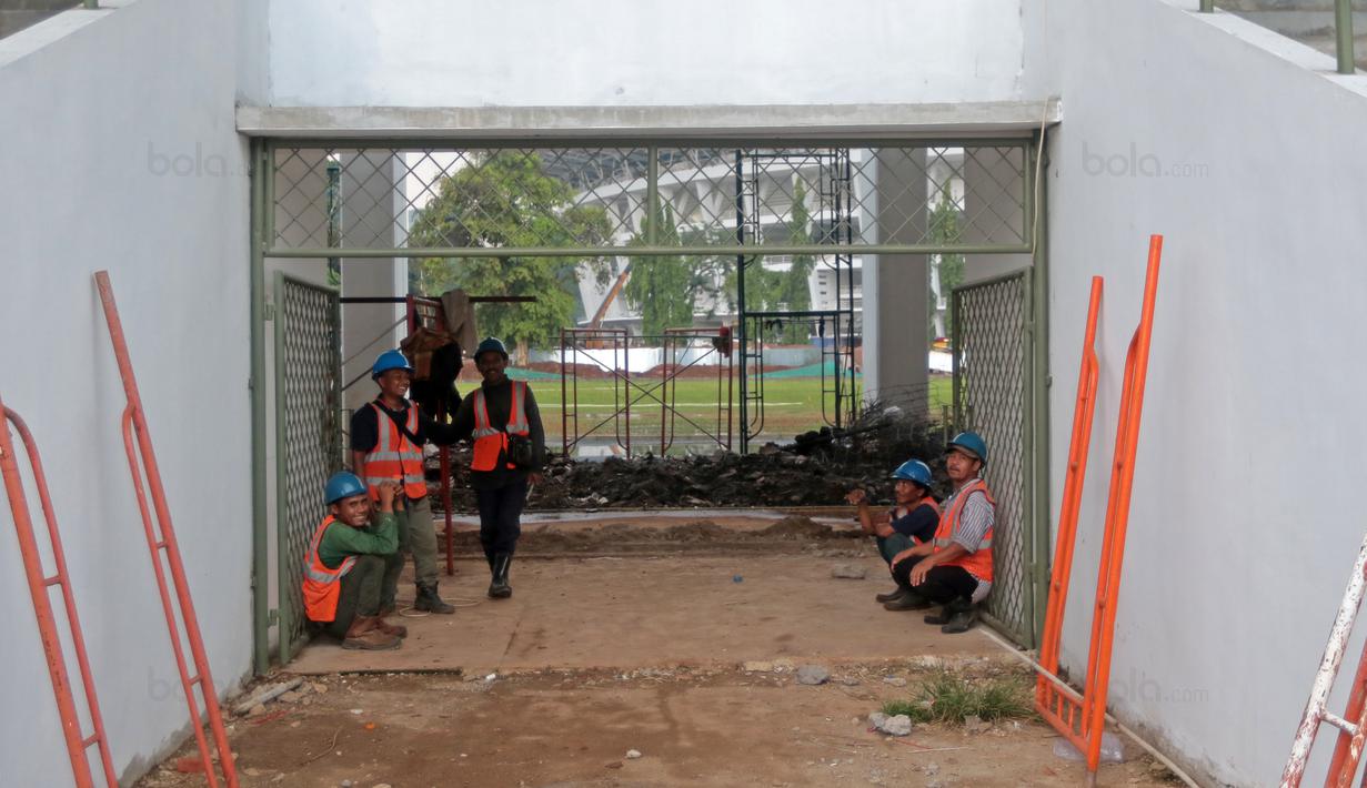 Pekerja berteduh saat hujan sebelum melanjutkan renovasi venue Atletik Stadion Madya di Kawasan Senayan Sport Center, Jakarta (12/10/2017). Renovasi tersebut menyambut Asian Games 2018. (Bola.com/Nicklas Hanoatubun)
