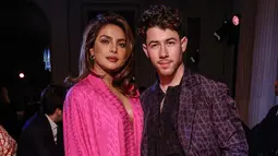 Priyanka Chopra (kiri) dan Nick Jonas menghadiri koleksi siap pakai Valentino Fall/Winter 2023-2024 yang dipresentasikan di Paris Fashion Week, Paris, Prancis, 5 Maret 2023. Chopra yang tampil serba pink membiarkan rambut cokelatnya tergerai, sementara untuk riasan dia memakai lipstik merah dan mata smokey. (Vianney Le Caer/Invision/AP)