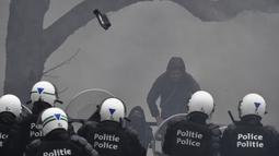 Sebuah proyektil dilempar ke udara saat polisi menghadapi pengunjuk rasa yang menentang tindakan COVID-19 di Brussels, Minggu (23/1/2022). Aksi demonstrasi tersebut berujung ricuh di mana bentrok antara pengunjuk rasa dan polisi tak terhindarkan. (AP Photo/Geert Vanden Wijngaert)