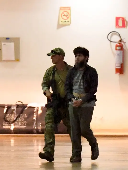 Polisi Brasil mengawal terduga teroris di hanggar Polisi Federal Brasil di bandara di Brasil, (21/7). 10 Orang terduga teroris itu berencana untuk menyerang pelaksanaan Olimpiade Brasil. ( AFP PHOTO/Evaristo SA)