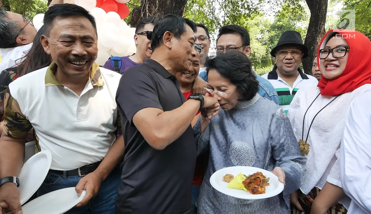 Kepala Staf Kepresidenan Moeldoko memberikan potongan tumpeng kepada sang istri, Koesni Harningsih saat merayakan ulang tahunnya yang ke-61 di Taman Suropati, Jakarta, Minggu (8/7). (Liputan6.com/Herman Zakharia)
