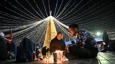 Keluarga-keluarga menyalakan lilin pada Hari Lilin Kecil ('Dia de las velitas'), di Bogota pada tanggal 7 Desember 2023. (Juan BARRETO/AFP)