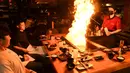 Pengunjung menikmati hidangan teppanyaki Jepang di Chinatown, Melbourne, Australia, Jumat (22/10/2021). Melbourne melonggarkan kebijakan lockdown mulai hari ini setelah berlangsung lebih dari 260 hari. (William WEST/AFP)