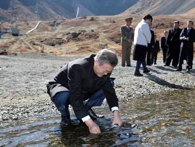 Presiden Korea Selatan Moon Jae-in memasukkan air kawah ke dalam botol di Gunung Paektu, Korea Utara, Kamis (20/9). Gunung Paektu merupakan gunung berapi yang dianggap sakral di Korea Utara. (Pyongyang Press Corps Pool via AP)